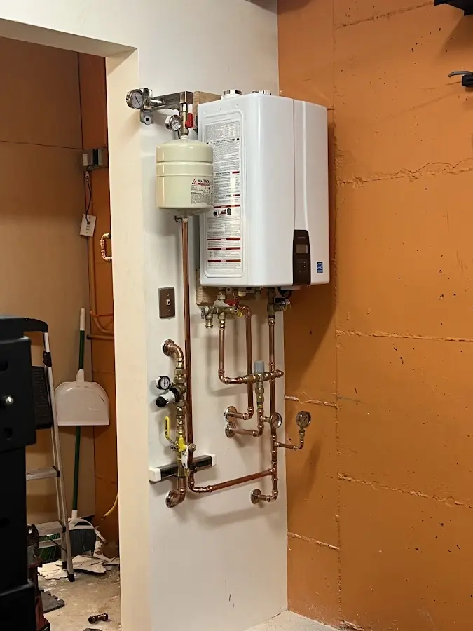 Plumbing technician inspecting water heater connections in Sennett